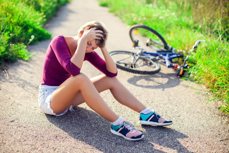 Woman who has fallen off a bicycle holding her head with a concussion