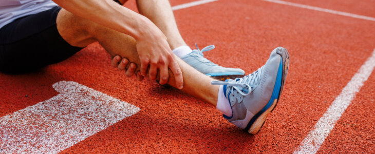 Runner on a track holding his shin